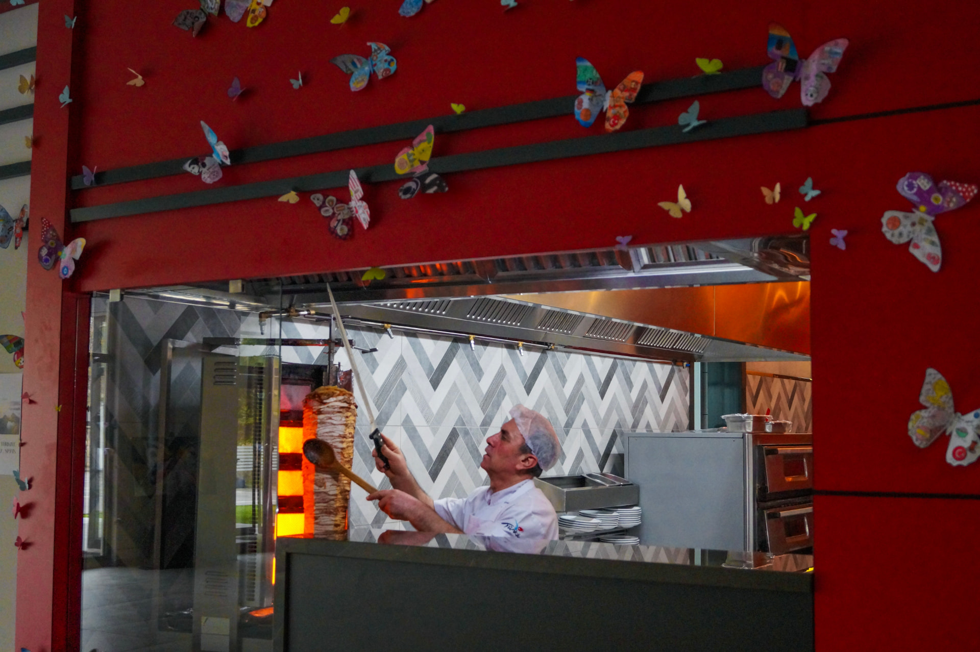 A cook working beneath a wall of student-made butterflies in the school canteen
