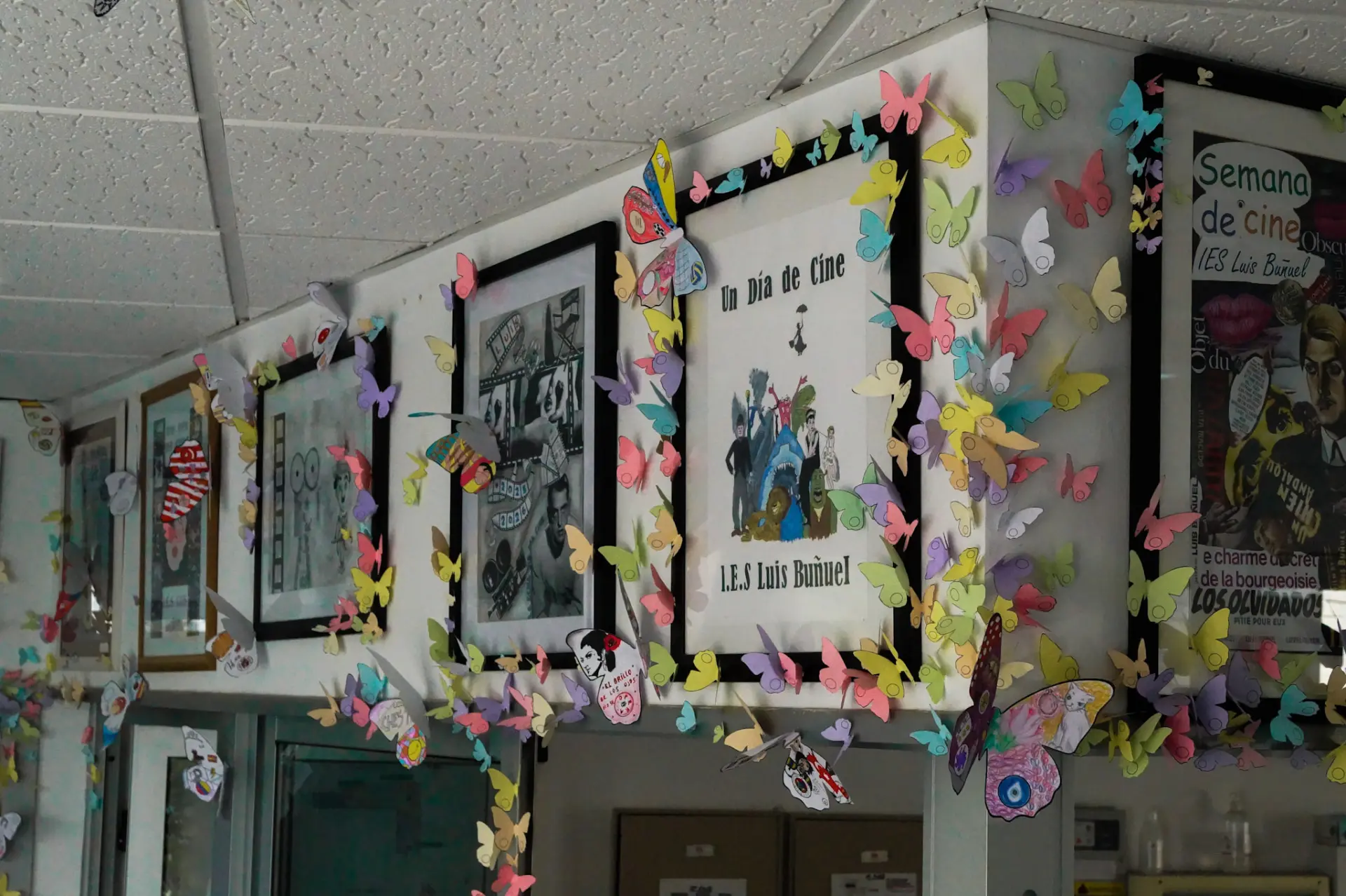 Colourful paper butterflies framing film posters along a school corridor at IES Luis Buñuel